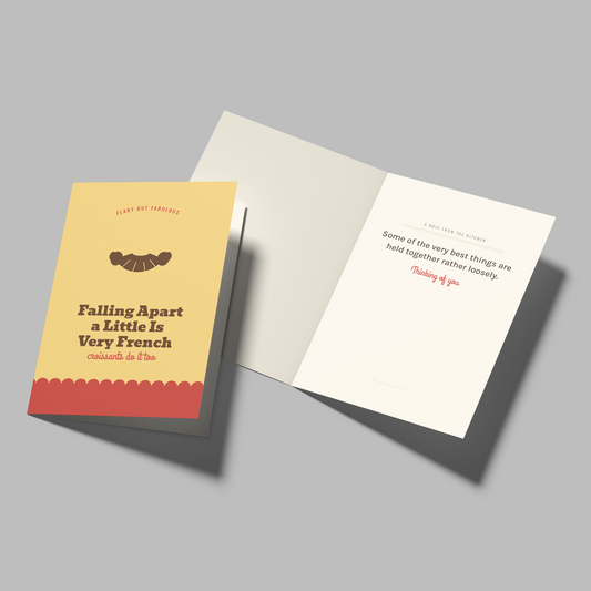 A greeting card set shown on a light gray background, featuring a closed card with a cream and red design titled 'Falling Apart a Little Is Very French' and an open card displaying a message on the inside.
