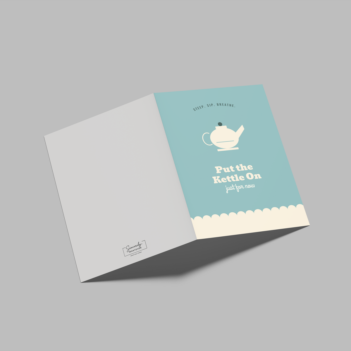 A folded square paper card or booklet shown open on a plain gray background. The right panel is light aqua with a white teapot illustration and the text 'Put the Kettle On just for you'; the left panel is white with a small logo near the bottom.